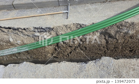 Green conduit in roadside trench for road repair and pipe laying background for infrastructure construction project. Telecommunication pipes Green conduit in roadside trench for road repair and pipe laying background for infrastructure construction project. Telecommunication pipes 139472075