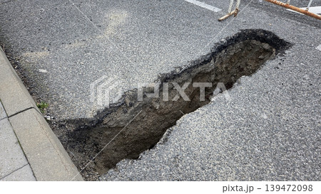 Deep elongated pothole and exposed asphalt trench on urban roadside for road repair background and public safety maintenance imagery Deep elongated pothole and exposed asphalt trench on urban roadside for road repair background and public safety maintenance imagery 139472098