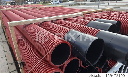 Close up of red corrugated drainage pipes with black end caps bundled for utility conduit installation and roadworks supply background 139472100