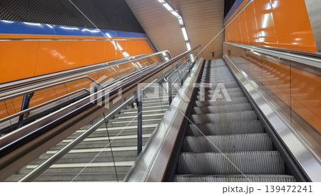 Madrid metro upward perspective of escalator and rails with glossy orange panels for background and architectural banner design Madrid metro upward perspective of escalator and rails with glossy orange panels for background and architectural banner design 139472241