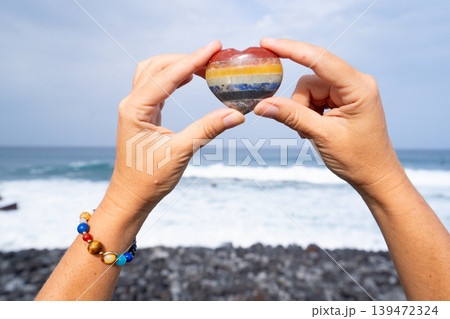 woman meditating on beach shore and holding crystal heart 139472324