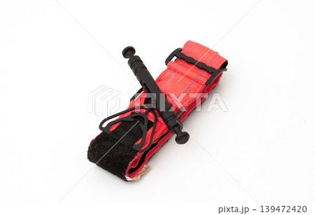 Red medical combat application tourniquet for emergency bleeding control isolated on white background. Red medical combat application tourniquet for emergency bleeding control isolated on white background. 139472420