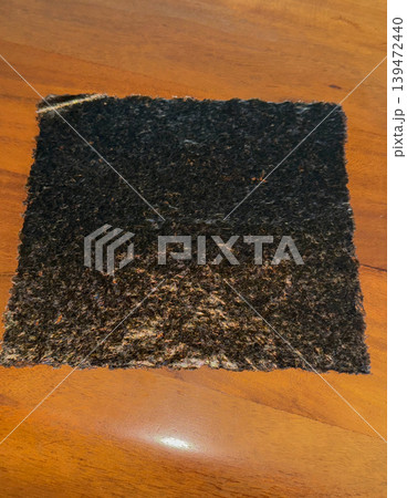 Close up photo of roasted nori seaweed sheet on a wooden surface. Natural dried seaweed texture used in Asian cuisine and sushi preparation Close up photo of roasted nori seaweed sheet on a wooden surface. Natural dried seaweed texture used in Asian cuisine and sushi preparation 139472440
