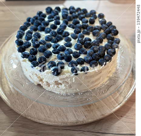 Rustic homemade blueberry cream cake on a glass serving plate with fresh berries and soft natural light. Trendy cozy food photography with bakery inspired aesthetic Rustic homemade blueberry cream cake on a glass serving plate with fresh berries and soft natural light. Trendy cozy food photography with bakery inspired aesthetic 139472448