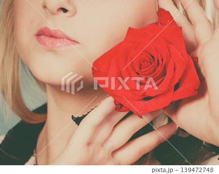 Closeup woman holding red rose near face. 139472748