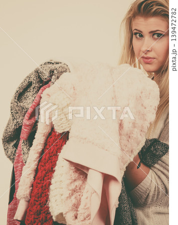 Woman holding big piles of clothing Woman holding big piles of clothing 139472782