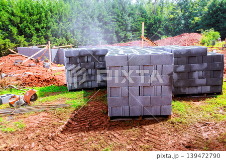 Workers prepare construction site with stacked building cement cinder blocks 139472790