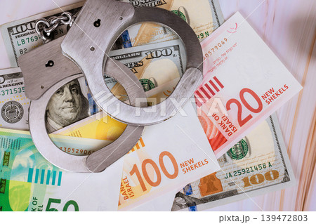 Handcuffs on US dollars Israeli new shekels at law event. 139472803