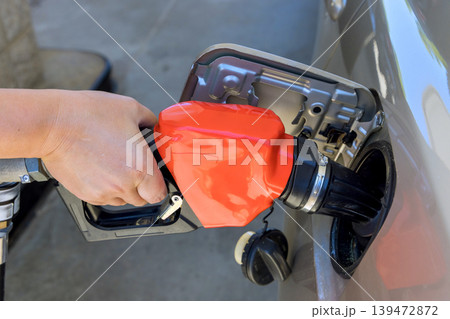 Person is refueling car at gas station with gas pump setting is bright activity is common. Person is refueling car at gas station with gas pump setting is bright activity is common. 139472872