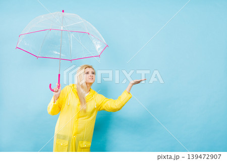 Woman wearing raincoat holding umbrella checking weather Woman wearing raincoat holding umbrella checking weather 139472907