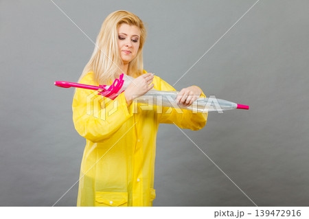 Woman wearing raincoat closing umbrella 139472916