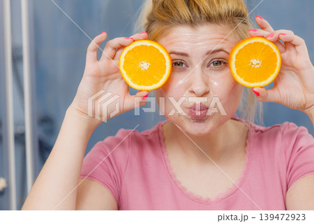 Woman having gel mask on face holding orange 139472923