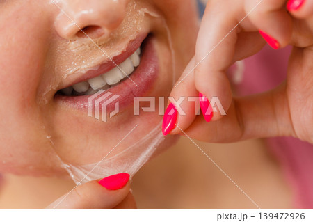 Woman peeling off gel mask from face Woman peeling off gel mask from face 139472926