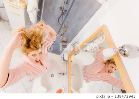 Woman looking at her very tangled blonde hair Woman looking at her very tangled blonde hair 139472943