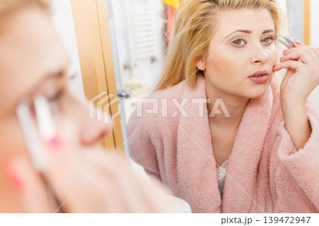 Woman tweezing eyebrows depilating with tweezers Woman tweezing eyebrows depilating with tweezers 139472947