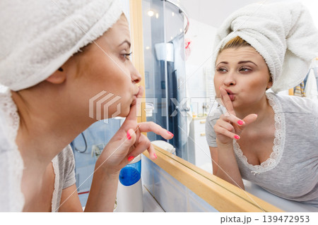 Woman looking at her reflection in mirror 139472953