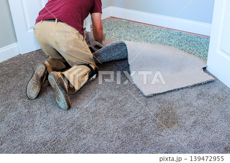 Worker removes old carpet, prepares to install new flooring during works renovation in room. Worker removes old carpet, prepares to install new flooring during works renovation in room. 139472955