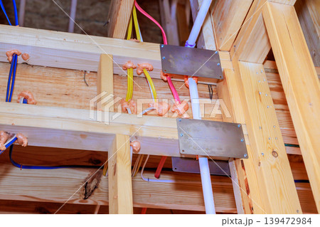 Workers install water pipes, electrical wires in building under construction with wooden beams, metal plates. Workers install water pipes, electrical wires in building under construction with wooden beams, metal plates. 139472984