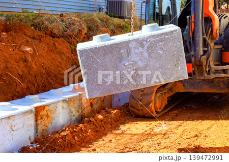 Large excavator is lifting concrete block at construction site while digging work 139472991