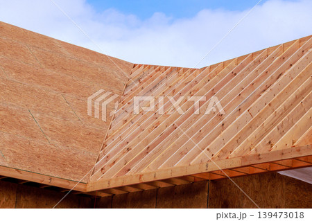 Workers build roof framework using wooden beams on new house during construction site. Workers build roof framework using wooden beams on new house during construction site. 139473018