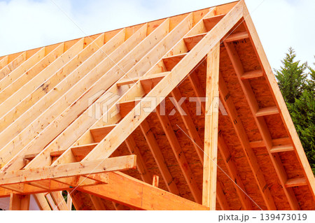 Workers are installing wooden beams to build roof frame at construction site Workers are installing wooden beams to build roof frame at construction site 139473019