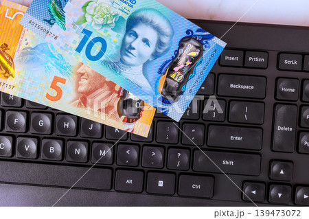 New Zealand banknotes on keyboard sit together on desk in an office setting New Zealand banknotes on keyboard sit together on desk in an office setting 139473072