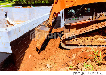 Excavator moves soil next to construction site where building foundation 139473126