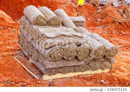 Sod rolls are neatly piled on wooden base at construction site during landscaping work 139473129