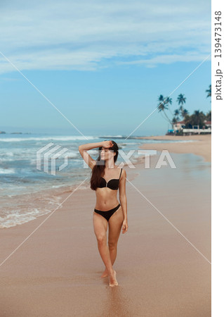 Beautiful woman in swimwear with copy space on the beach. Portrait of pretty girl with slim tanned sexy body in black bikini enjoying life. Summer lifestyle. Vacation Beautiful woman in swimwear with copy space on the beach. Portrait of pretty girl with slim tanned sexy body in black bikini enjoying life. Summer lifestyle. Vacation 139473148