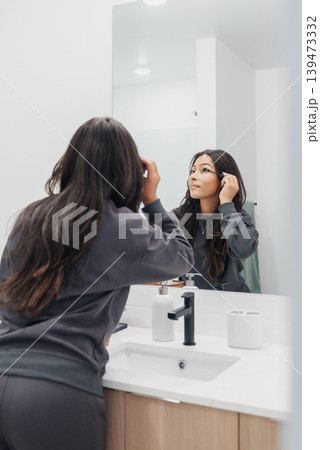 Quick Makeup Fix In Bathroom. Woman Completes Makeup Touchup Before Heading Out Door. Caring Woman Straightens Her Appearance With Quick Mascara Touchup Reflected In Mirror Quick Makeup Fix In Bathroom. Woman Completes Makeup Touchup Before Heading Out Door. Caring Woman Straightens Her Appearance With Quick Mascara Touchup Reflected In Mirror 139473332