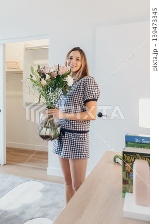 Joyful Lady Arranging Bright Blossoms. Smiling Woman Decorates With Colorful Flowers At Home. Cheerful Woman Lovingly Arranges And Organizes Colorful Flowers In Bright Home Setting 139473345