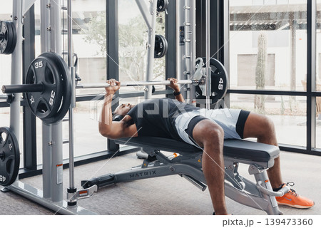 Strong Lifter Effort. Dedicated Athlete Performing Heavy Barbell Push With Determination. Serious Competitor Executing Fullrange Heavy Bench Press Under Intense Focus And Gym Ambiance 139473360