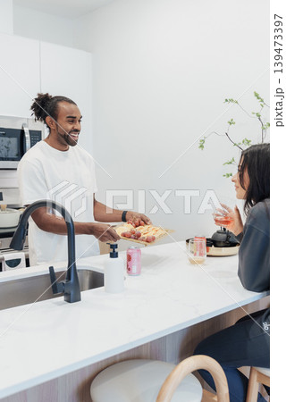 Black Man Handing Bowl Across Kitchen Counter To Asian Woman, Candid Midaction Shot, Stools Tucked Under Island, Everyday Support And Care, Food Jars And Kettle Present, Warm Domestic Rhythm Black Man Handing Bowl Across Kitchen Counter To Asian Woman, Candid Midaction Shot, Stools Tucked Under Island, Everyday Support And Care, Food Jars And Kettle Present, Warm Domestic Rhythm 139473397