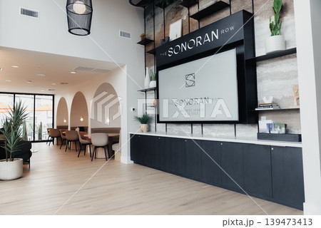 Bright Modern Reception Area With Desk, Soft Natural Light, Large Signage Wall Displaying Logo, Long Black Reception Counter, Potted Plants, Wooden Parquet Flooring, Seating Alcove Bright Modern Reception Area With Desk, Soft Natural Light, Large Signage Wall Displaying Logo, Long Black Reception Counter, Potted Plants, Wooden Parquet Flooring, Seating Alcove 139473413