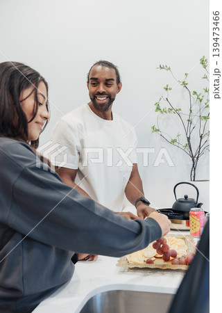 Asian Woman Chopping Fruit While Black Man Watches With Supportive Smile, Closeup Vertical Frame, Modern Sink Area, Hands In Motion, Warm Rapport, Informal Cooking Lesson And Friendly 139473466