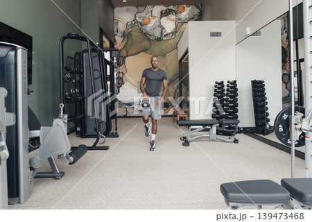Black Man Trainer Sprinting Across Gym. Wide Shot Of Trainer Midstride On Rubber Floor, Dynamic Motion Blur, Weights And Machines In Background, Focused Expression, Athletic Wear, High 139473468