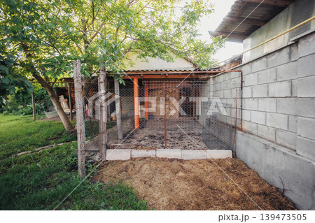 Rustic Chicken Coop And Enclosed Pen With Straw Bedding And Concrete Block Wall, Raw Farm Texture And Earthy Tones Ideal For Agricultural, Sustainable Living And Backyard Livestock Visuals. Rustic Chicken Coop And Enclosed Pen With Straw Bedding And Concrete Block Wall, Raw Farm Texture And Earthy Tones Ideal For Agricultural, Sustainable Living And Backyard Livestock Visuals. 139473505