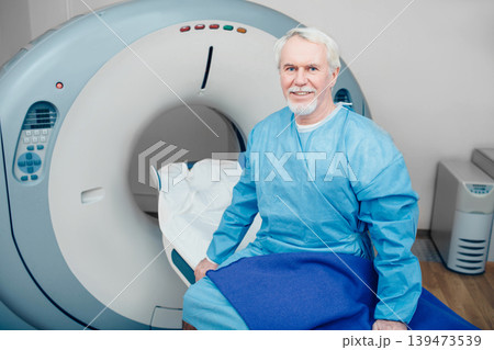 senior man sitting on scanner table. waiting for CT scan senior man sitting on scanner table. waiting for CT scan 139473539