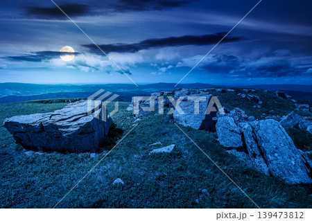 mountainous landscape during summertime at night. full moon over boulders and rock formations surrounded grassy hills. picture of an untouched highland. backdrop for fiction art or mystery concept mountainous landscape during summertime at night. full moon over boulders and rock formations surrounded grassy hills. picture of an untouched highland. backdrop for fiction art or mystery concept 139473812