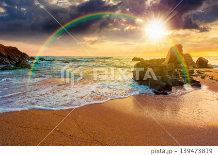 sunset over huge stones on the sandy beach. wonderful holiday season background at the sea. clouds on the blue sky above horizon. view of waves washing the shore. weather with rainbow sunset over huge stones on the sandy beach. wonderful holiday season background at the sea. clouds on the blue sky above horizon. view of waves washing the shore. weather with rainbow 139473819