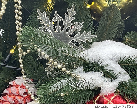 Christmas decorations on snow-covered tree branches featuring ornaments and festive lights Christmas decorations on snow-covered tree branches featuring ornaments and festive lights 139473855