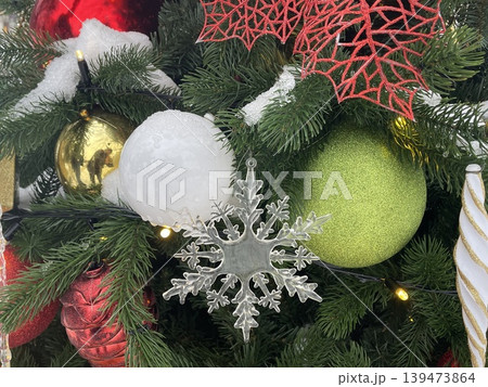 Christmas tree adorned with festive ornaments including snowflake and colorful baubles 139473864