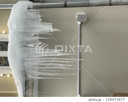 Ice formations with large icicles hanging from building, creating winter scene suitable for background 139473877