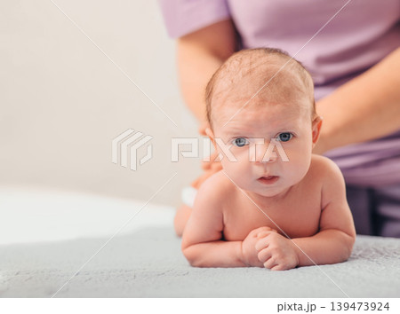A healthcare provider cares for a newborn baby during a routine examination, ensuring the infant's health and comfort in a clinic setting 139473924