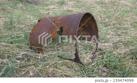 View of a ruined rusty metal cylinder lying on dry and green grass in a field under daylight. Concept of abandoned technology and nature reclamation View of a ruined rusty metal cylinder lying on dry and green grass in a field under daylight. Concept of abandoned technology and nature reclamation 139474099
