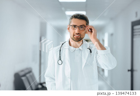 portrait of a clinical doctor adjusting his glasses at clinic corridor. 139474133
