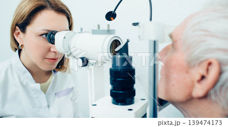 Doctor Optometrist examining old man's eyes with special eye equipment Doctor Optometrist examining old man's eyes with special eye equipment 139474173