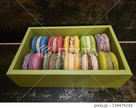 Assorted colorful french macarons in a light green gift box on a dark textured background. Concept of gourmet sweet gift Assorted colorful french macarons in a light green gift box on a dark textured background. Concept of gourmet sweet gift 139474188