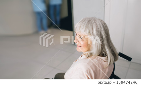 Smiling senior woman in wheelchair sitting at the hospital corridor. Go home after discharge from hospital 139474246