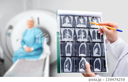 A healthcare worker examines CT scan images while seated patient awaits results in a medical clinic setting 139474259